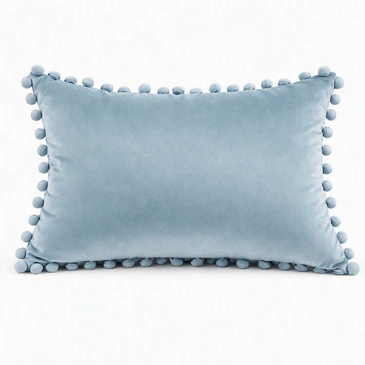 A light blue rectangular throw pillow with pom-pom trim along all edges, shown against a plain white background. -YPWBA2014-SEA