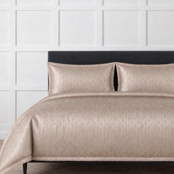 The Judith Leiber Couture Embossed Bedding Set by Ann Gish, shown in ecru, featuring an embossed duvet cover and two matching shams displayed on a bed against a white paneled wall. YSETDVEMK-ECR YSETDVEMQ-ECR