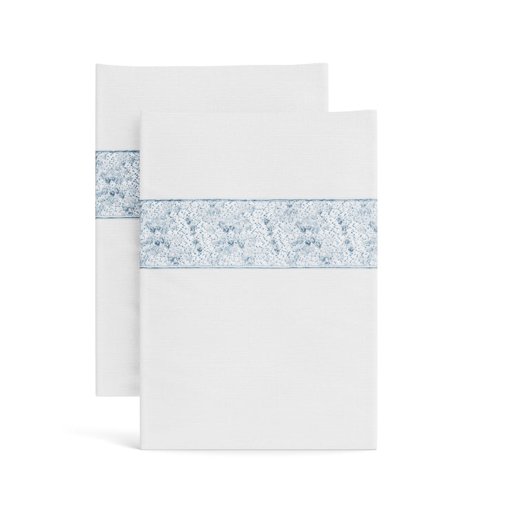 Stacked white Minaudiere pillowcases from the Judith Leiber Couture x Ann Gish collection, detailed with a light blue sequined border band that echoes the jeweled Minaudiere motif. - PCMIK‑WHI‑BLE PCMIS‑WHI‑BLE