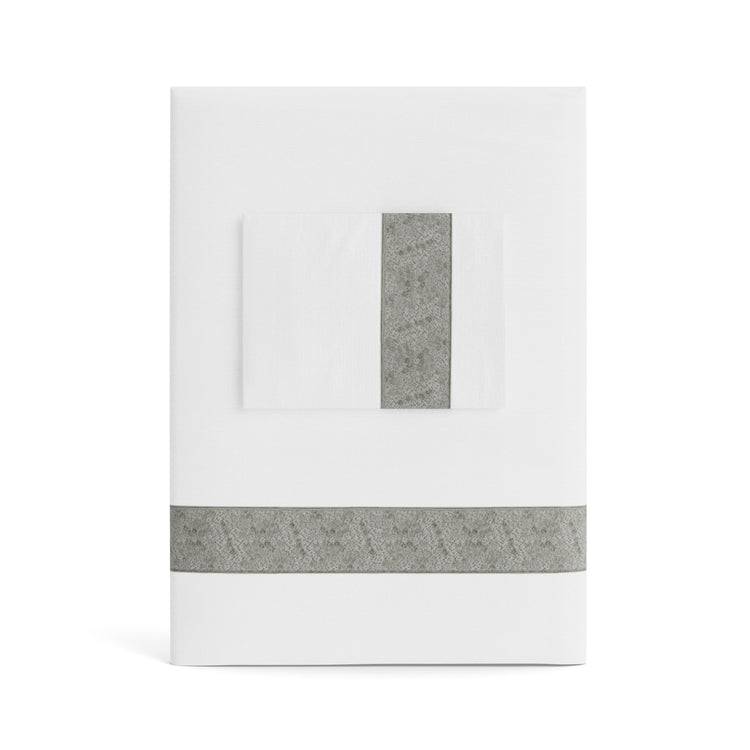 A folded white Minaudiere Sheet Set by Judith Leiber Couture x Ann Gish, shown with its matching pillowcase on top, featuring a metallic grey sequenced border band that mirrors the jeweled sparkle of the Minaudiere design. - SSMIK-WHI-MET SSMIQ-WHI-MET