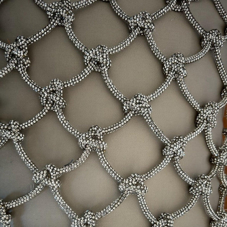 A close-up of a silver beaded mesh or net fabric with repeating diamond-shaped lattice patterns and knotted bead details on a beige silk fabric background. - PWPE1812-MYS PWPE2222-MYS