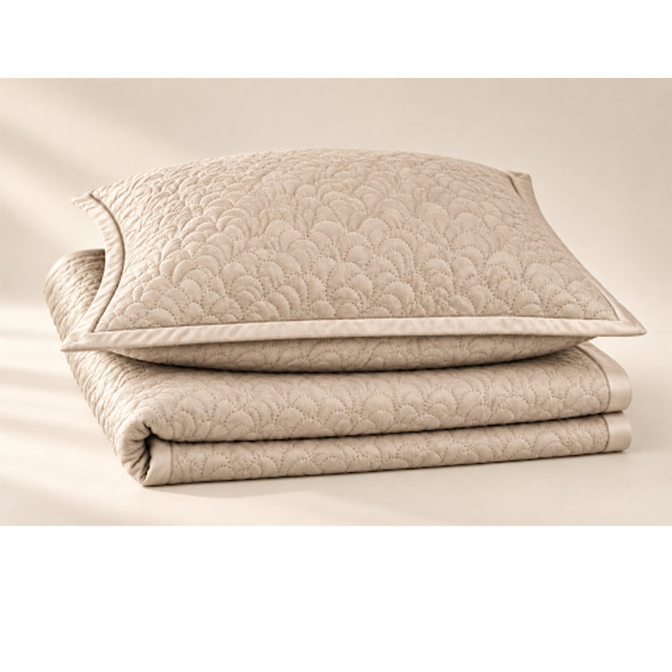 A folded Shells Coverlet Set from the Judith Leiber Couture x Ann Gish collection, shown as a product silo with the matching sham placed on top, featuring the scalloped quilted pattern in a light neutral tone. - YSETCOSHK-BON YSETCOSHQ-BON